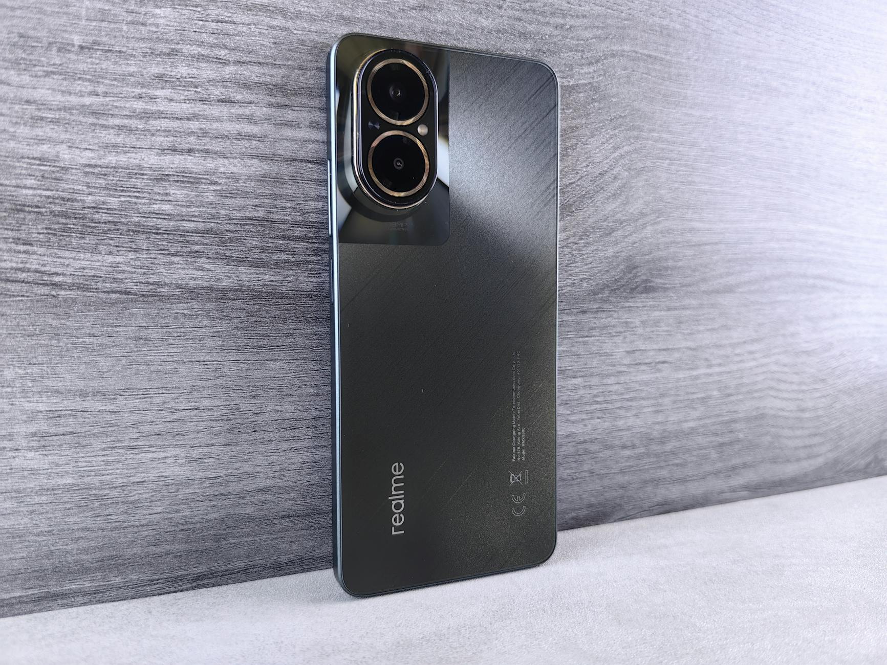 Close-up of a modern Realme smartphone with dual cameras on a wooden background.