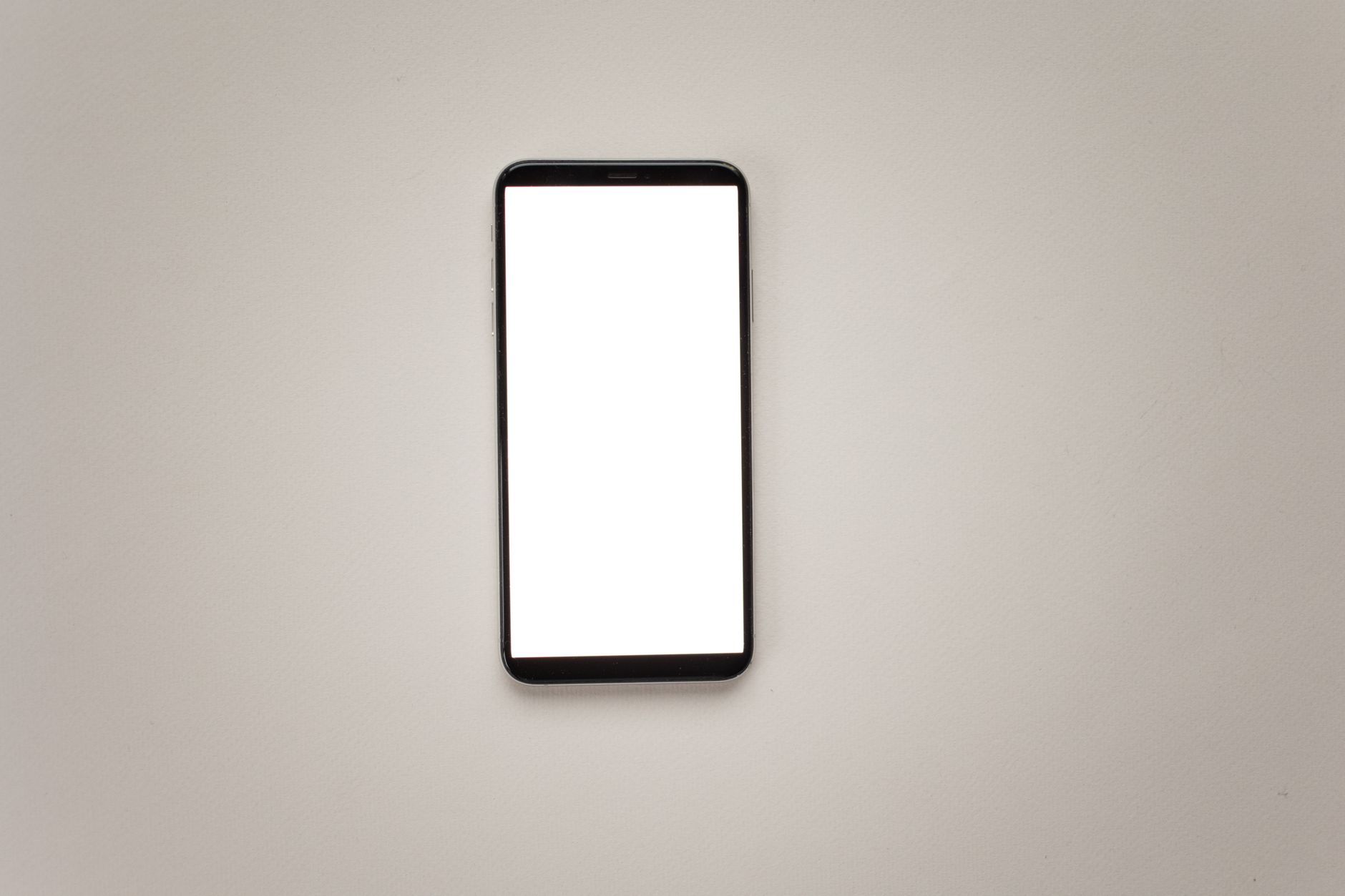 Top view of a smartphone with a blank screen for mockup design on a neutral background.
