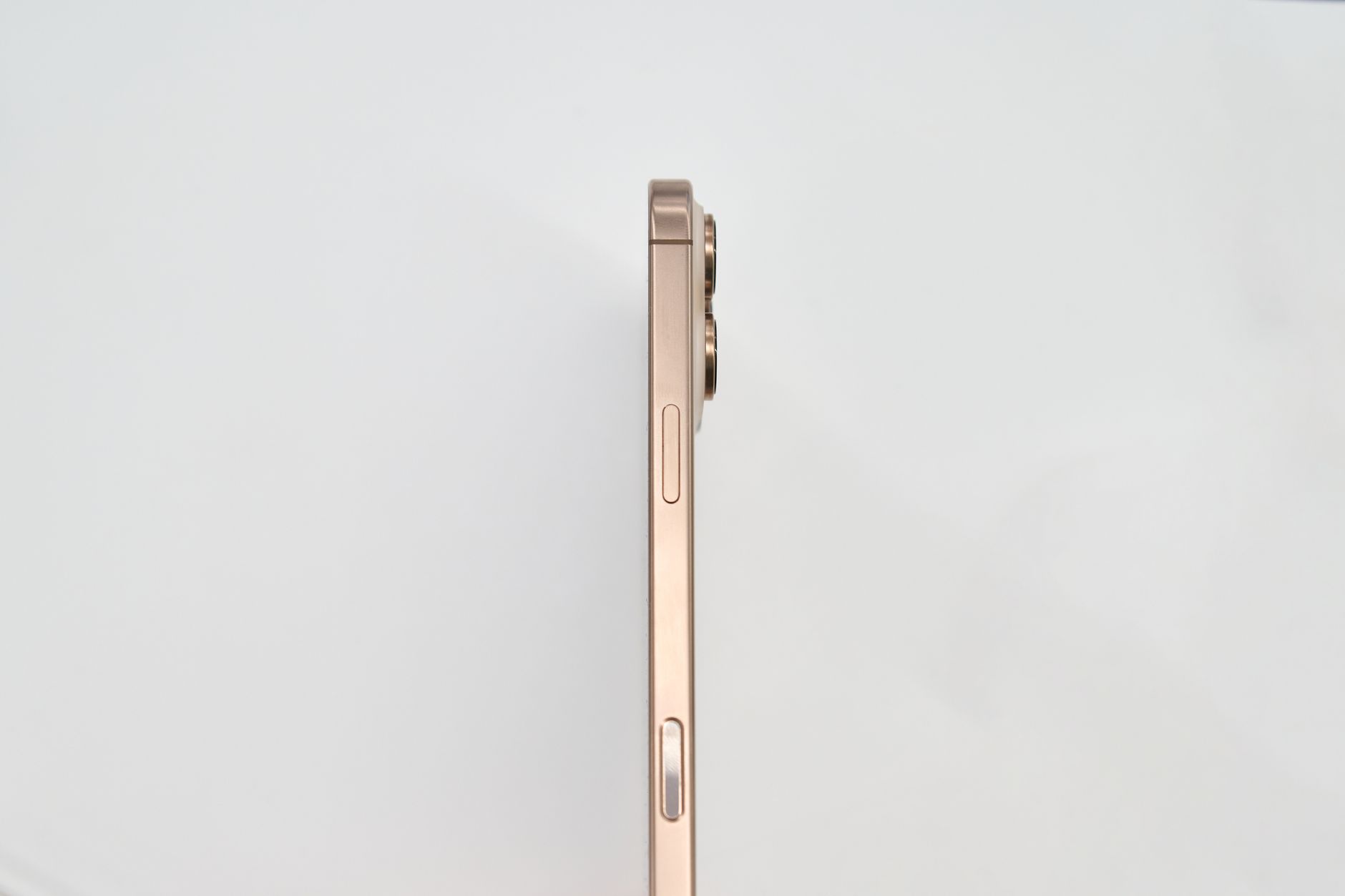 Minimalist side view of a gold smartphone on white background.
