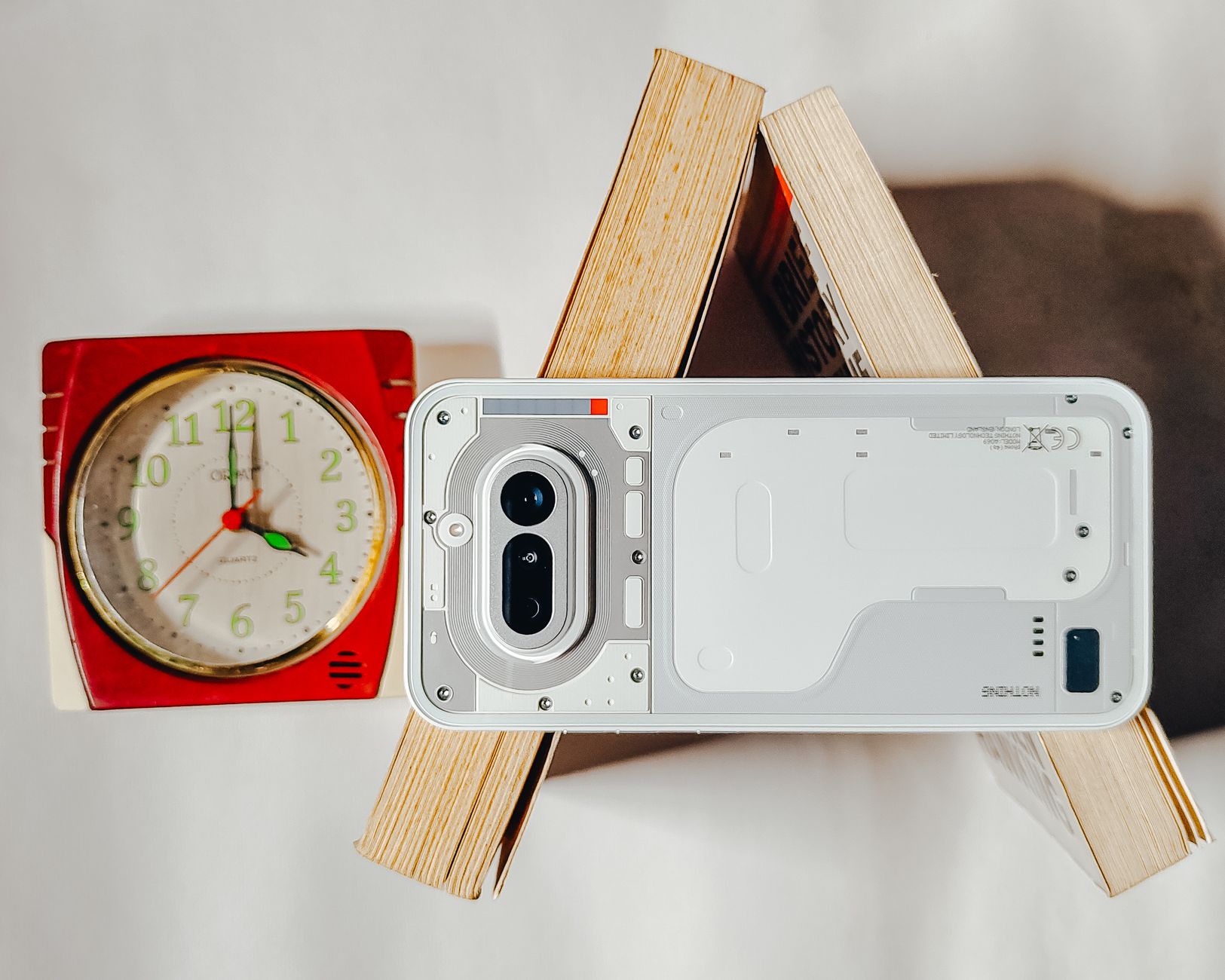 Artistic composition with a modern smartphone and vintage clock on books creating a unique flat lay design.