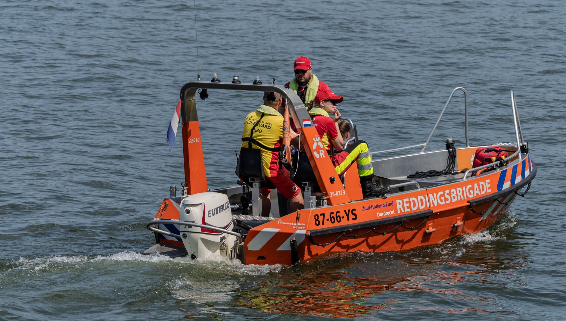 Lifeguards on a Reddingsbrigade boat patrolling water for safety and rescue operations.