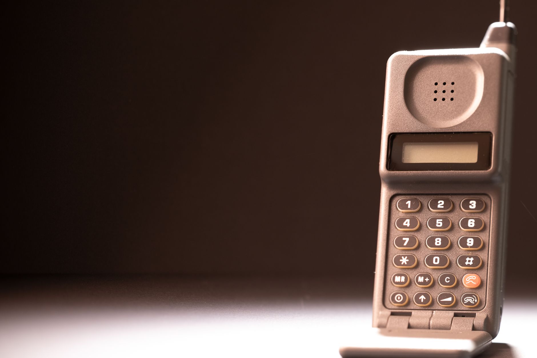 Vintage mobile phone with keypad and antenna on a dark background, emphasizing retro technology.