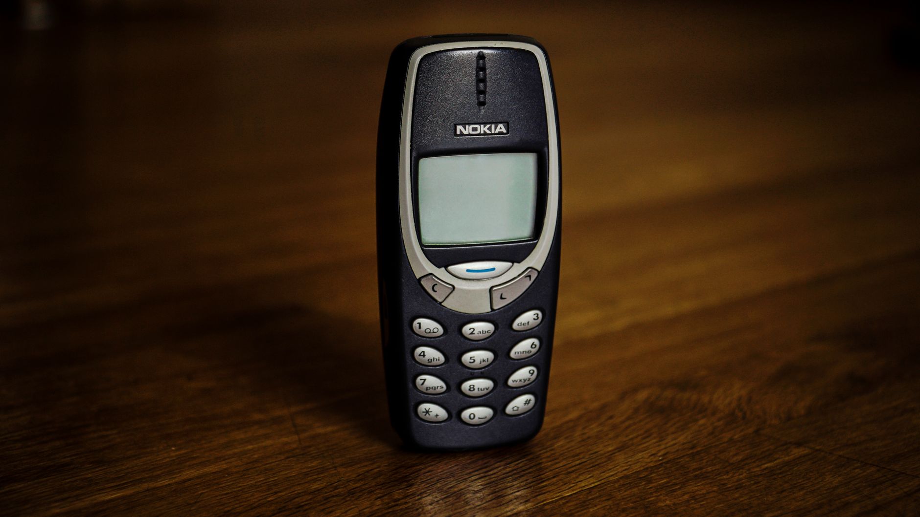 Small old mobile phone with monochrome screen and buttons placed on wooden table