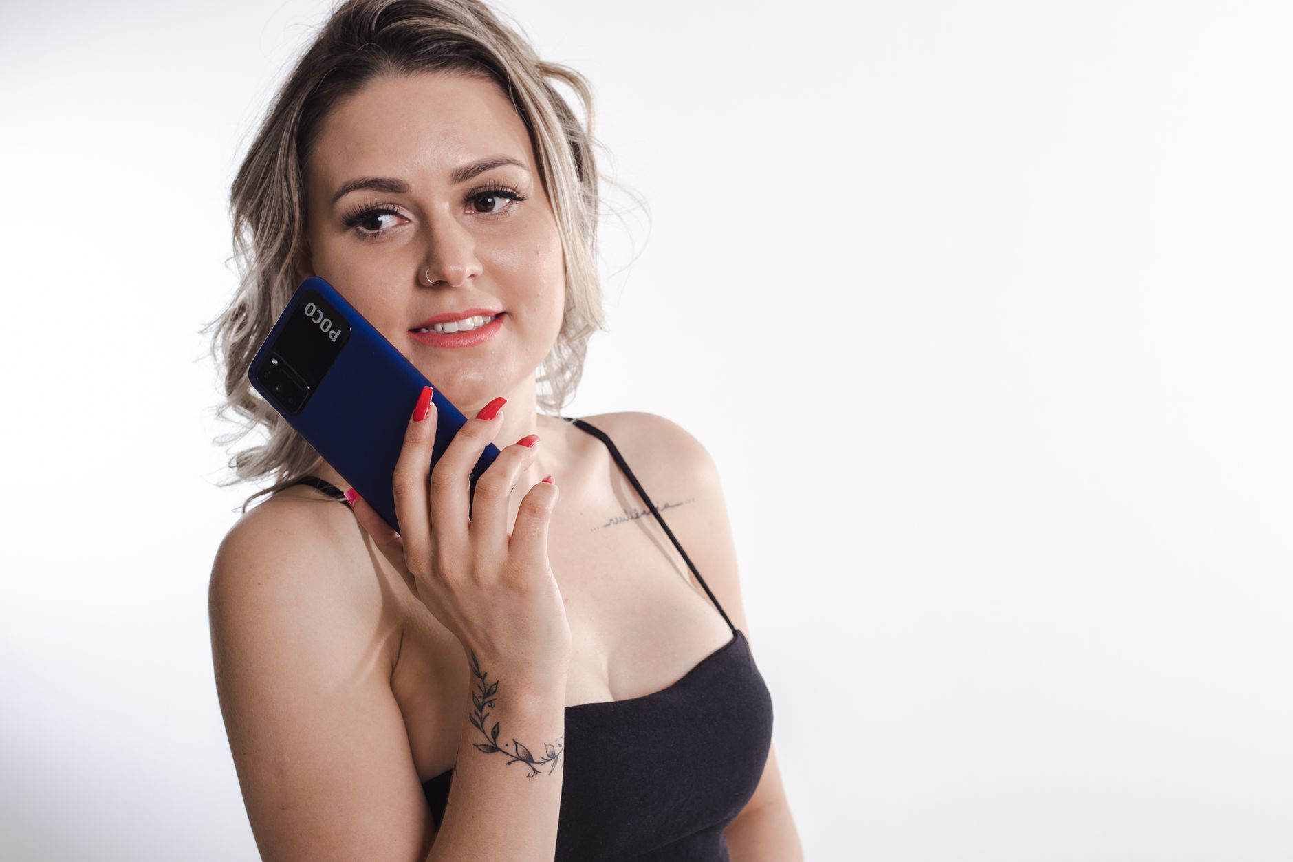 Caucasian woman smiling while holding a blue smartphone against a white background.