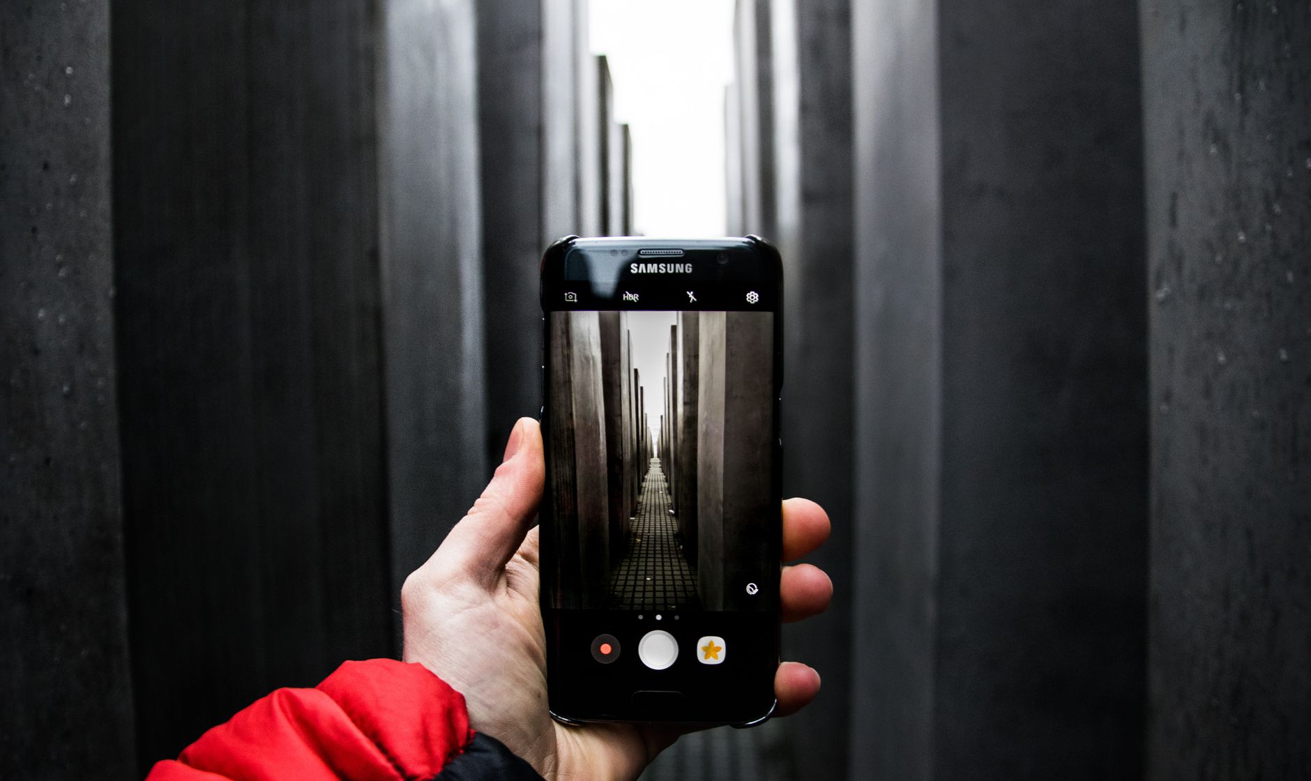 A smartphone photograph of the Berlin Holocaust Memorial, capturing somber reflections.