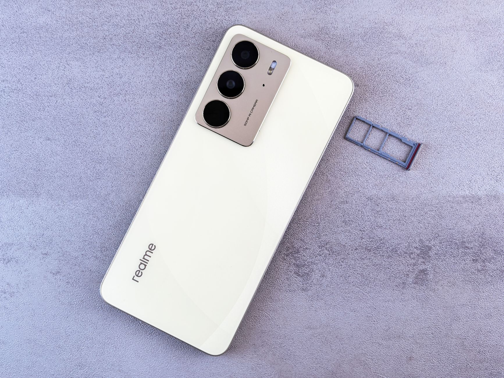 Elegant white smartphone on a grey surface next to a SIM card tray, showcasing modern design.