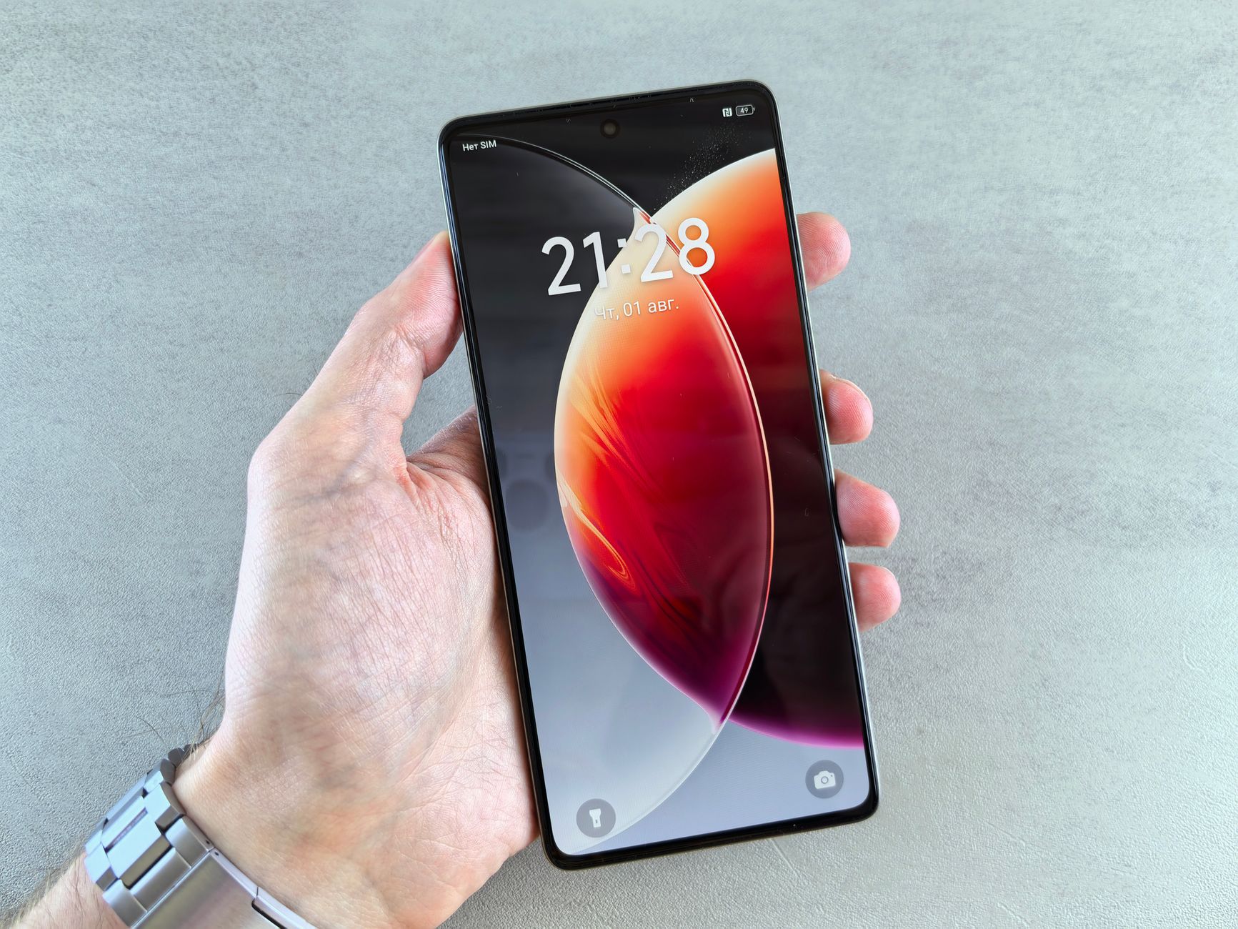 A person holding a modern smartphone displaying digital time and colorful wallpaper.