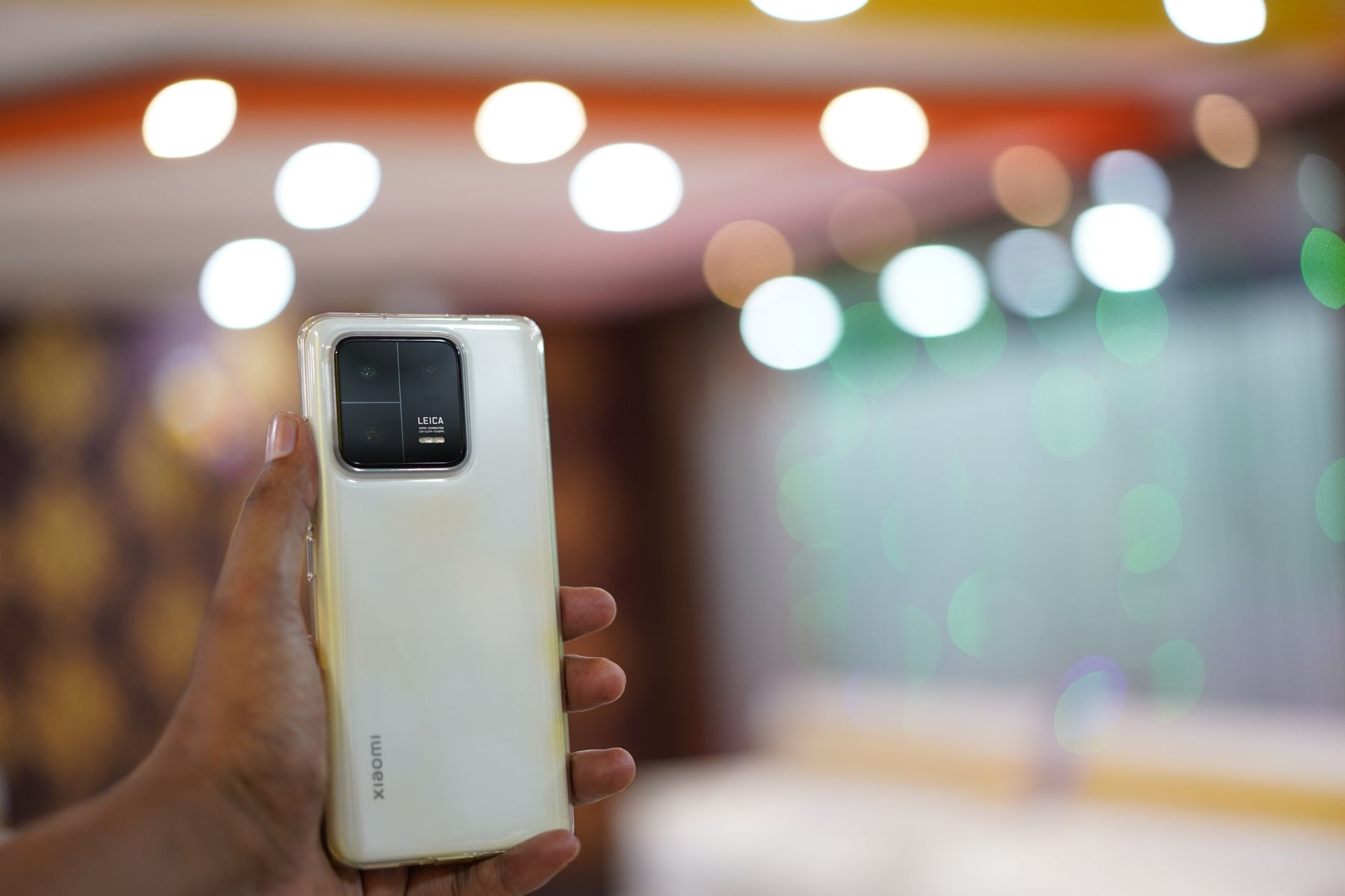 Person holding a smartphone with a blurred bokeh background indoors.