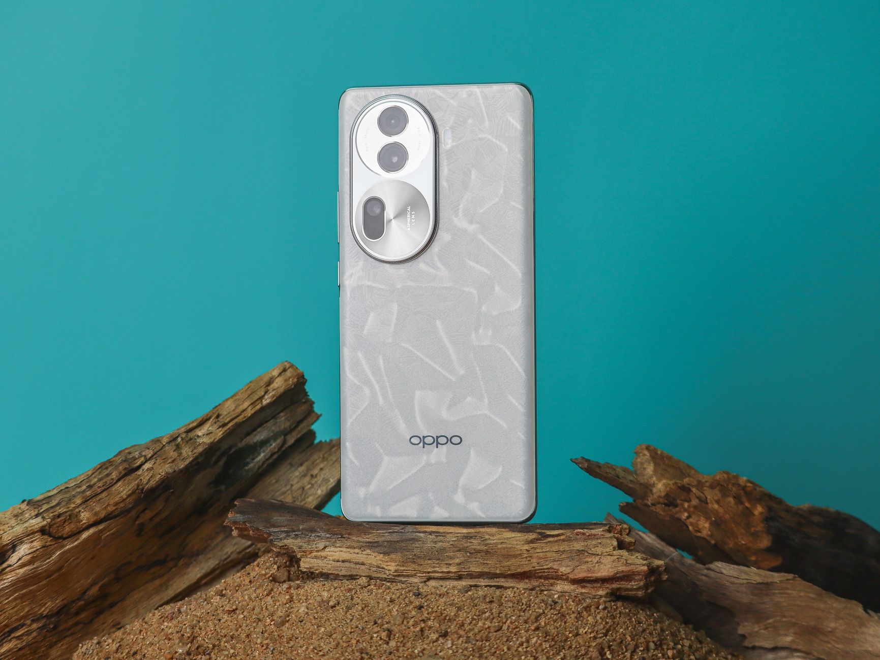 Modern smartphone with textured back on sand with wooden element against a vibrant blue background.