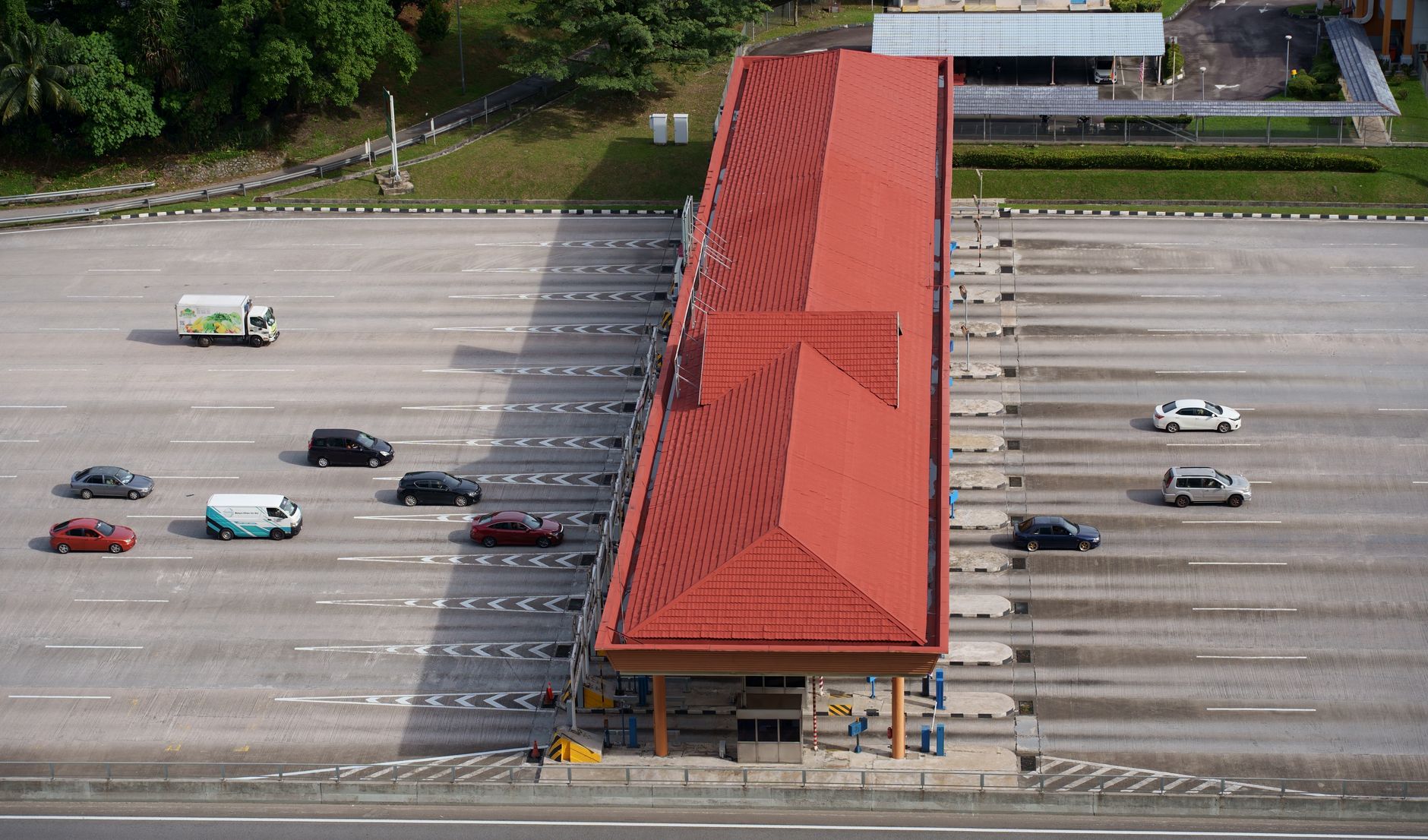 High angle aerial shot of a toll plaza with cars and trucks on an expansive highway.