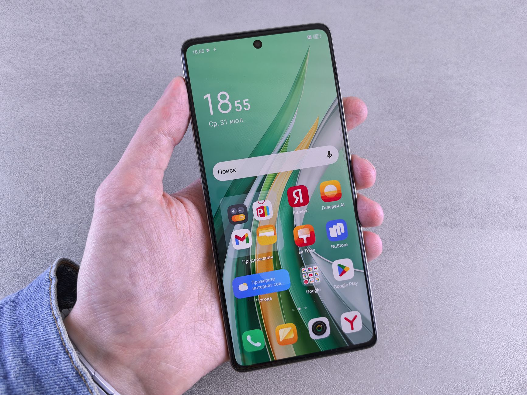Close-up of a hand holding a smartphone with a vibrant app-filled screen against a neutral background.