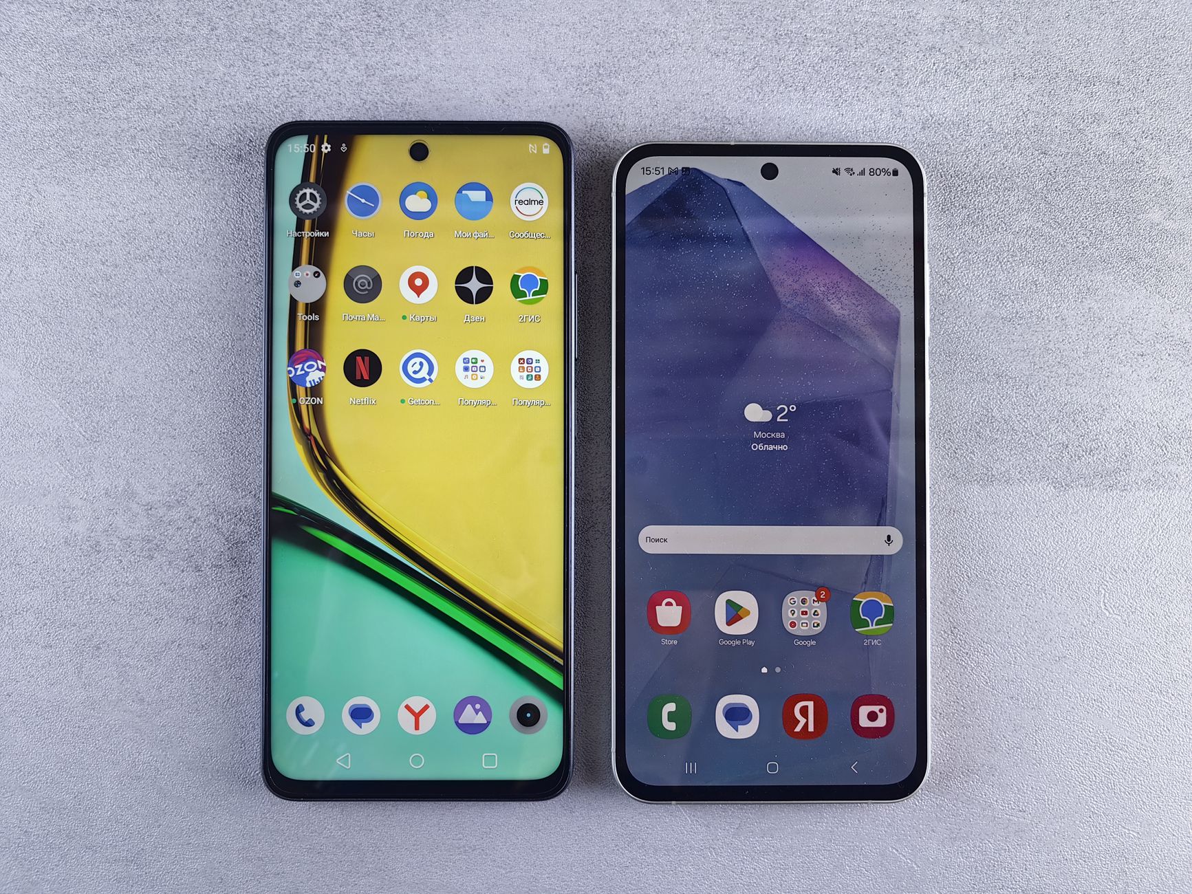 Top-down view of two modern smartphones with home screens displayed on a textured surface.