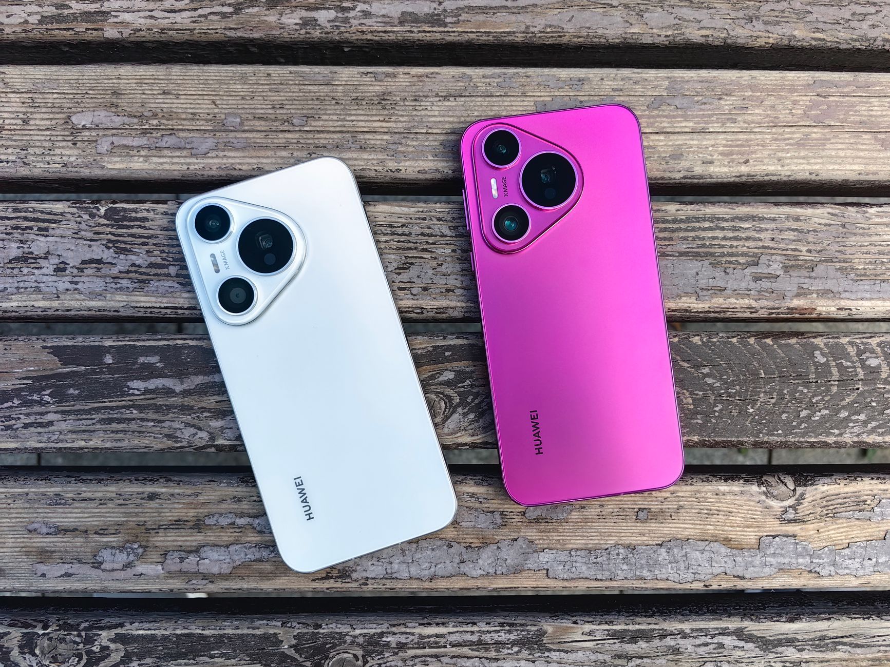 Two Huawei smartphones in white and pink on rustic wooden slats.