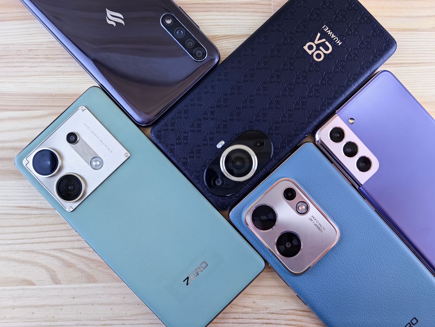 Close-up of multiple smartphones arranged on a wooden surface, showcasing variety.