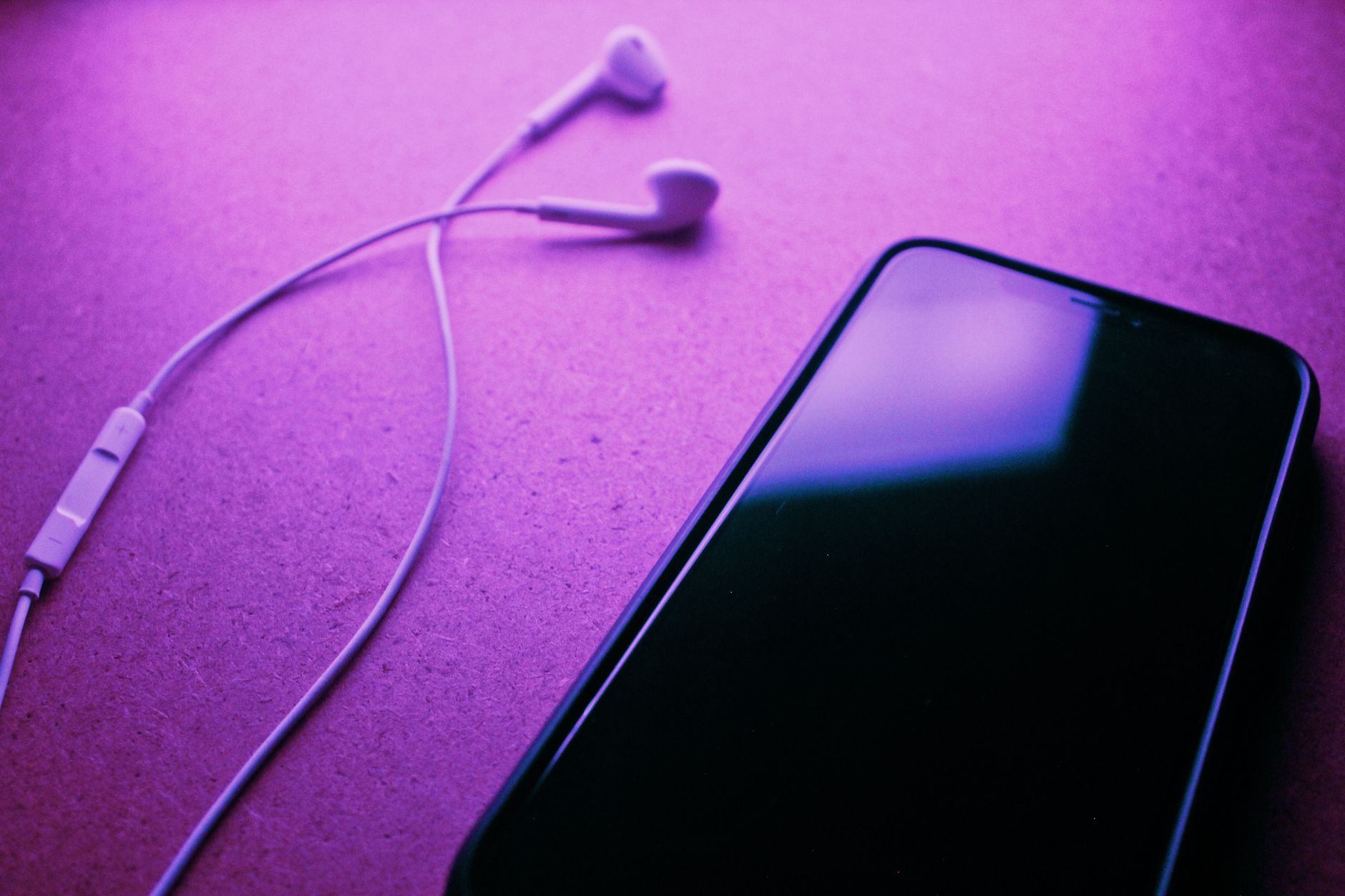 A close-up image of a smartphone and earphones against a purple background, highlighting modern technology.