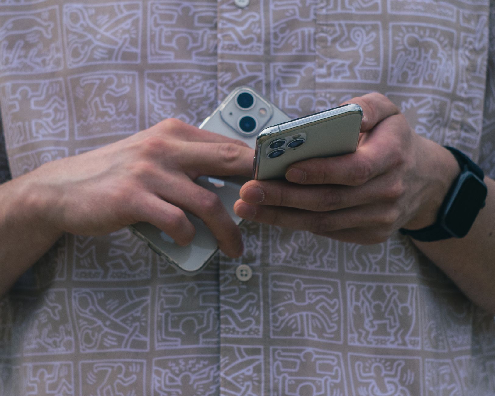 Detail of hands holding two smartphones, showcasing modern technology usage.