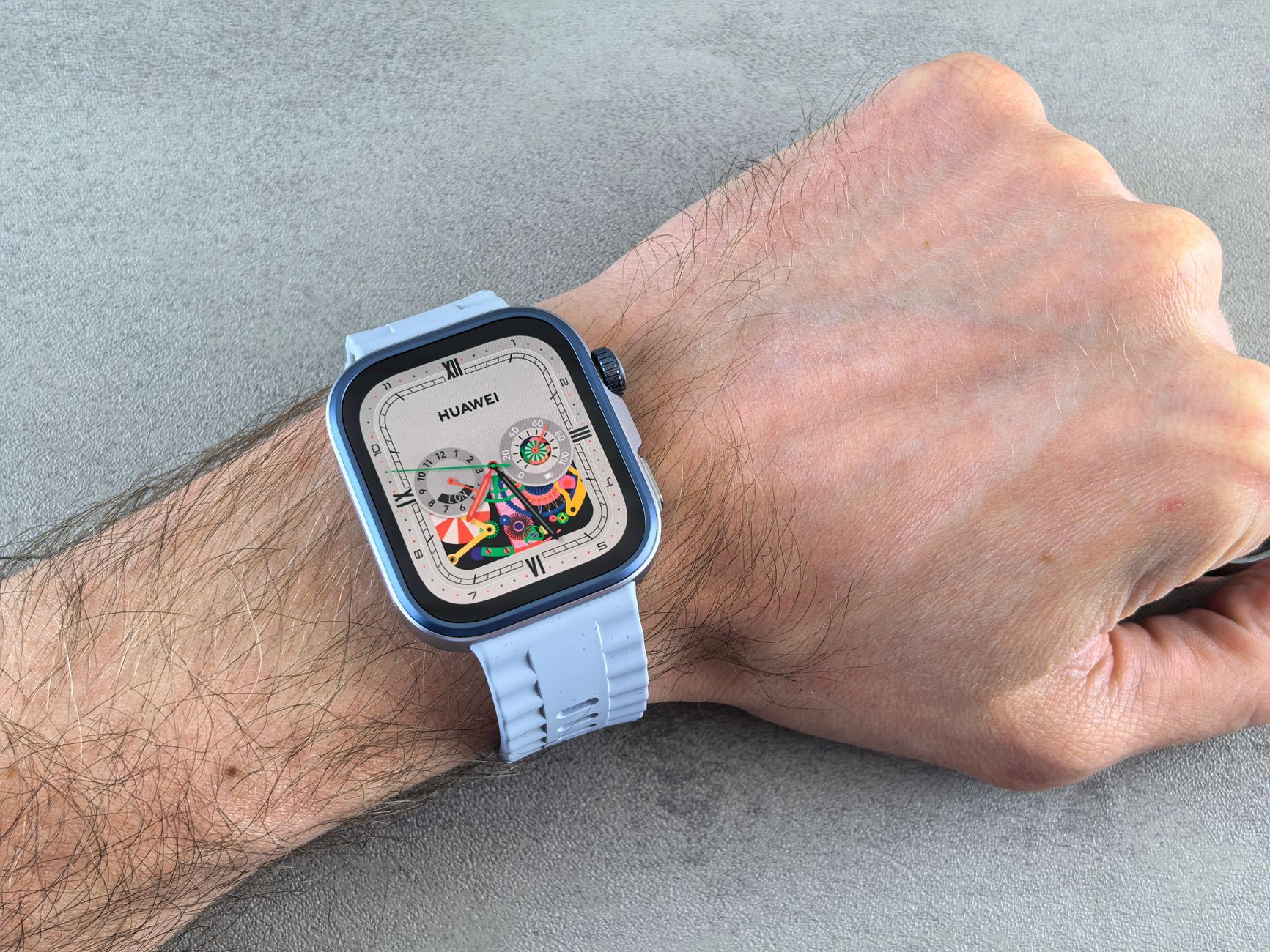 A detailed view of a Huawei smartwatch with a colorful display, worn on a human wrist.