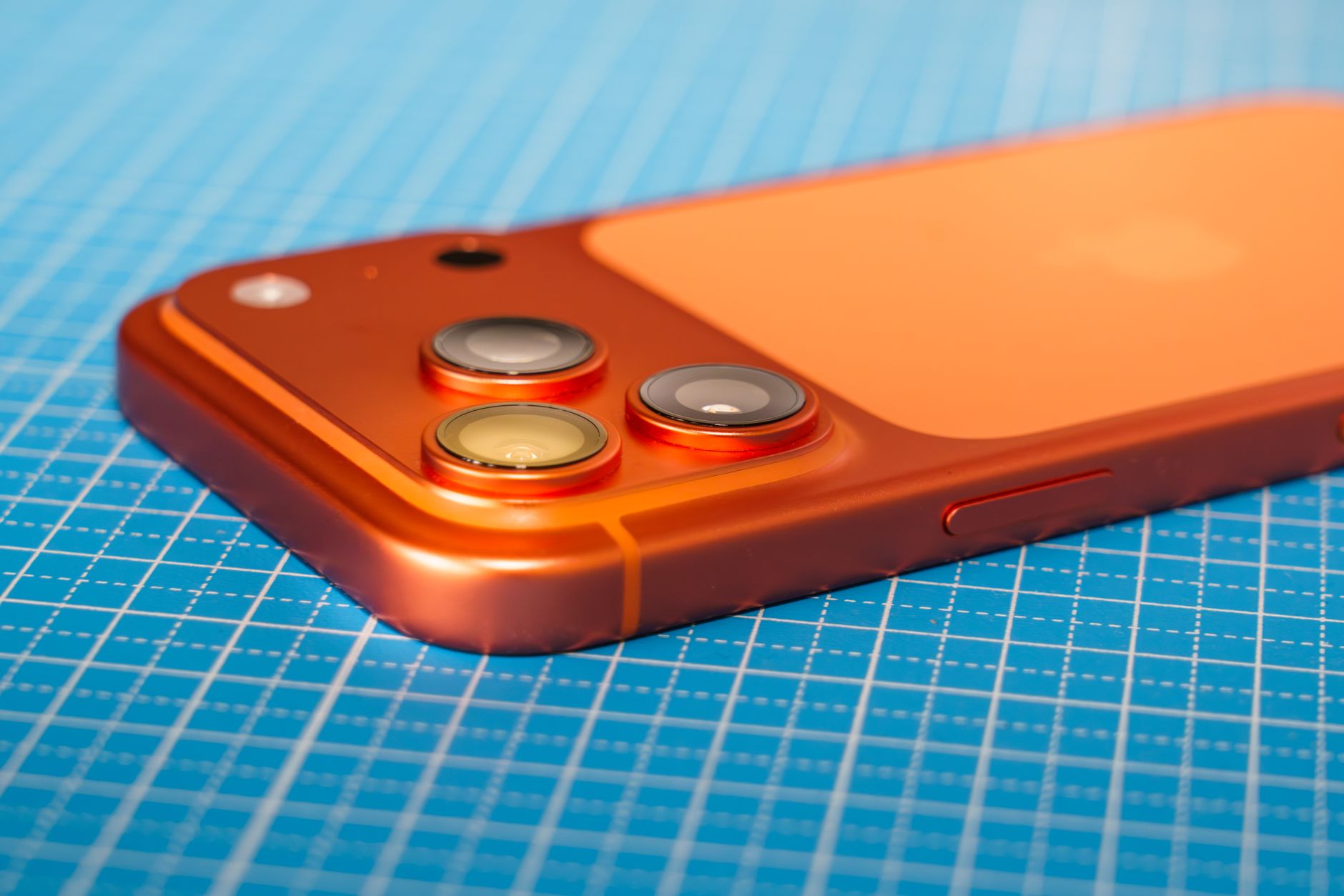 Modern smartphone with a triple camera on a vibrant grid surface, showcasing advanced technology.