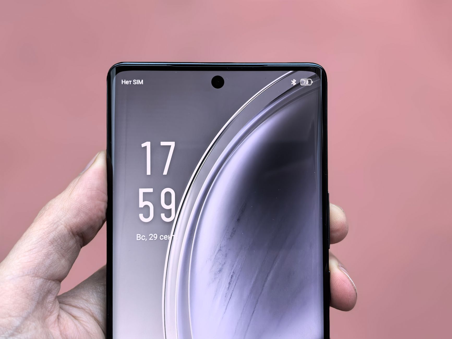 Close-up shot of a smartphone display showing time and reflection in a hand's grip.