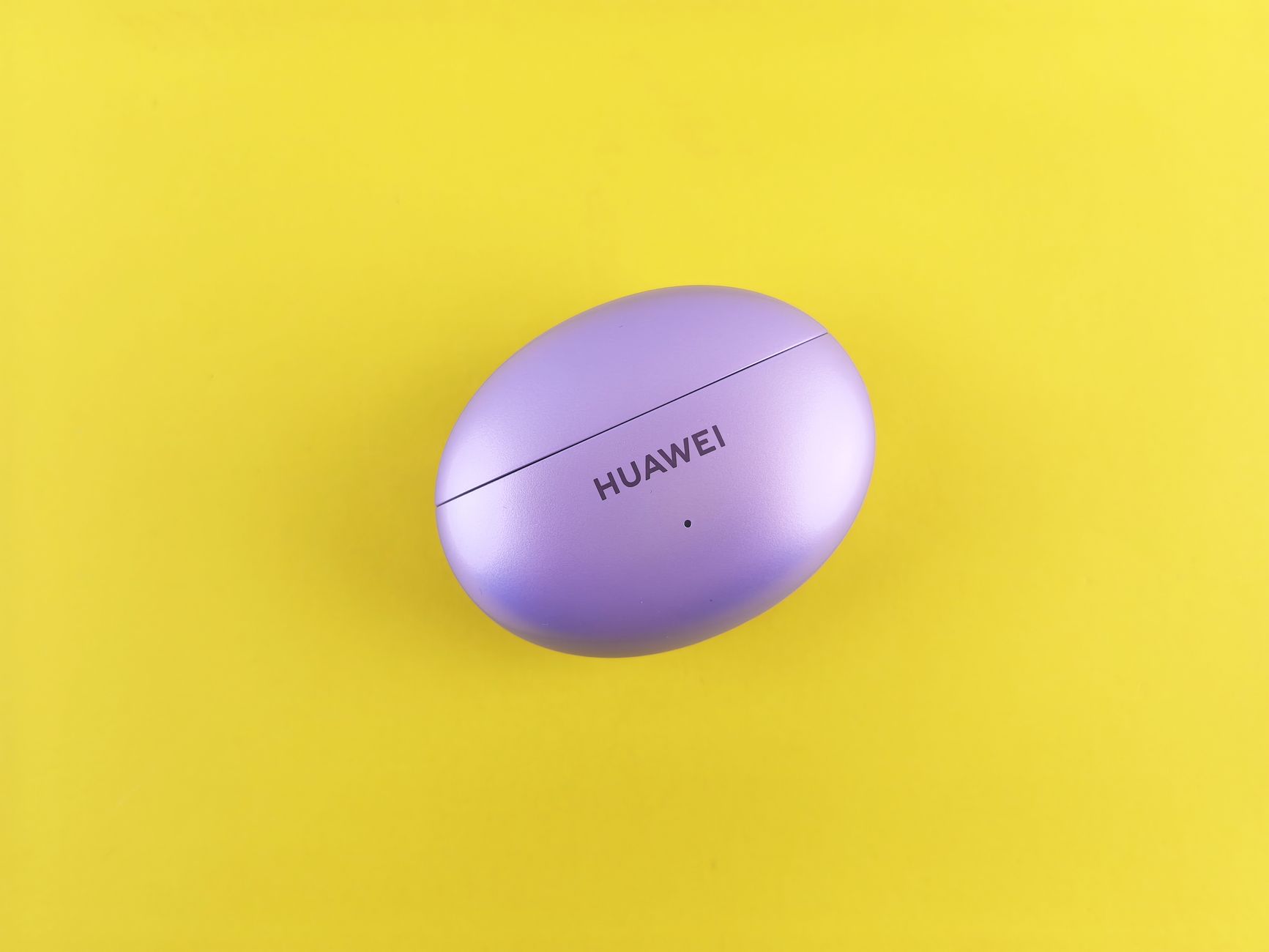 Purple Huawei earbuds case on a vibrant yellow backdrop, showcasing minimal design.