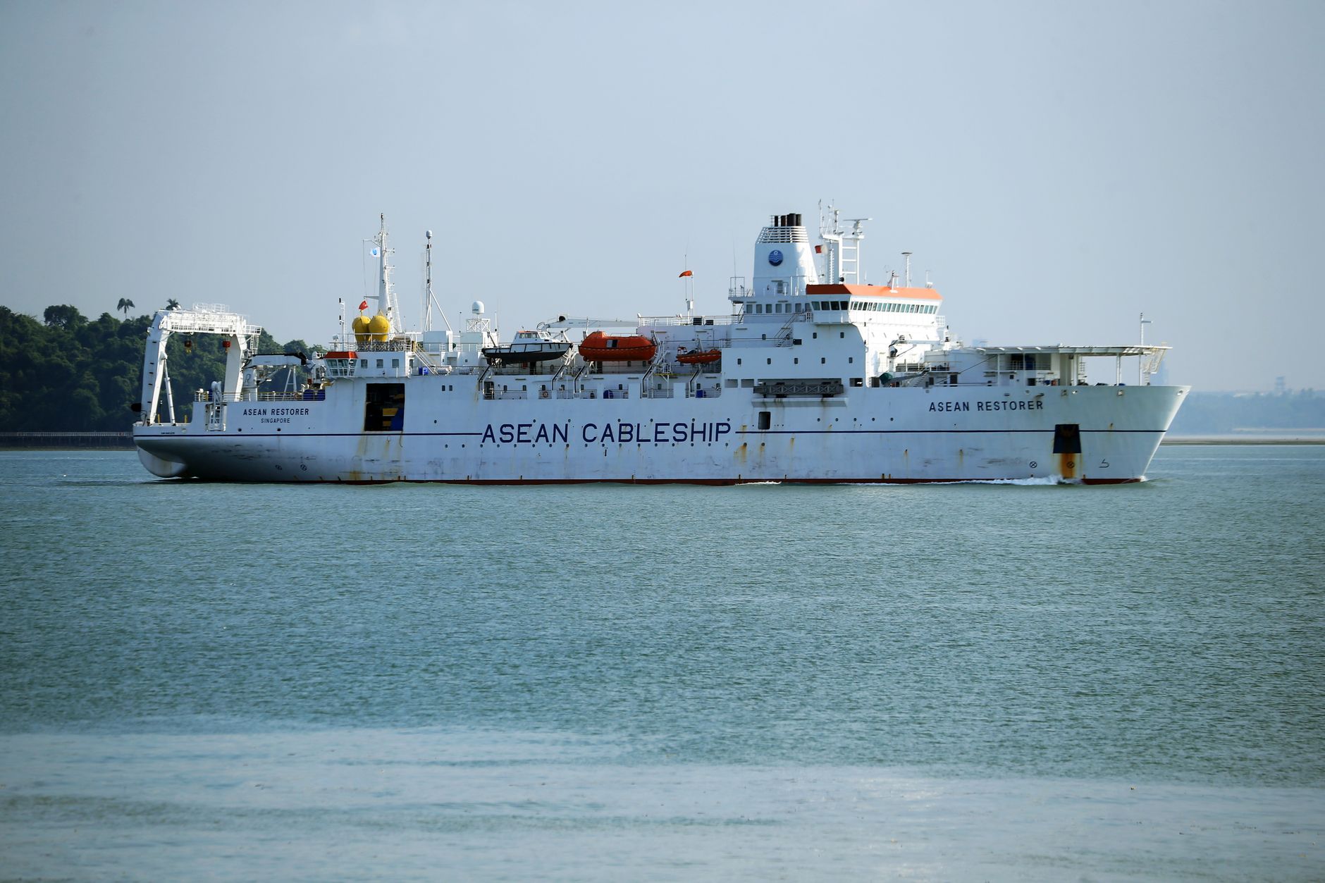 A cable ship named ASEAN Restorer navigating in clear ocean waters, highlighting maritime technology.