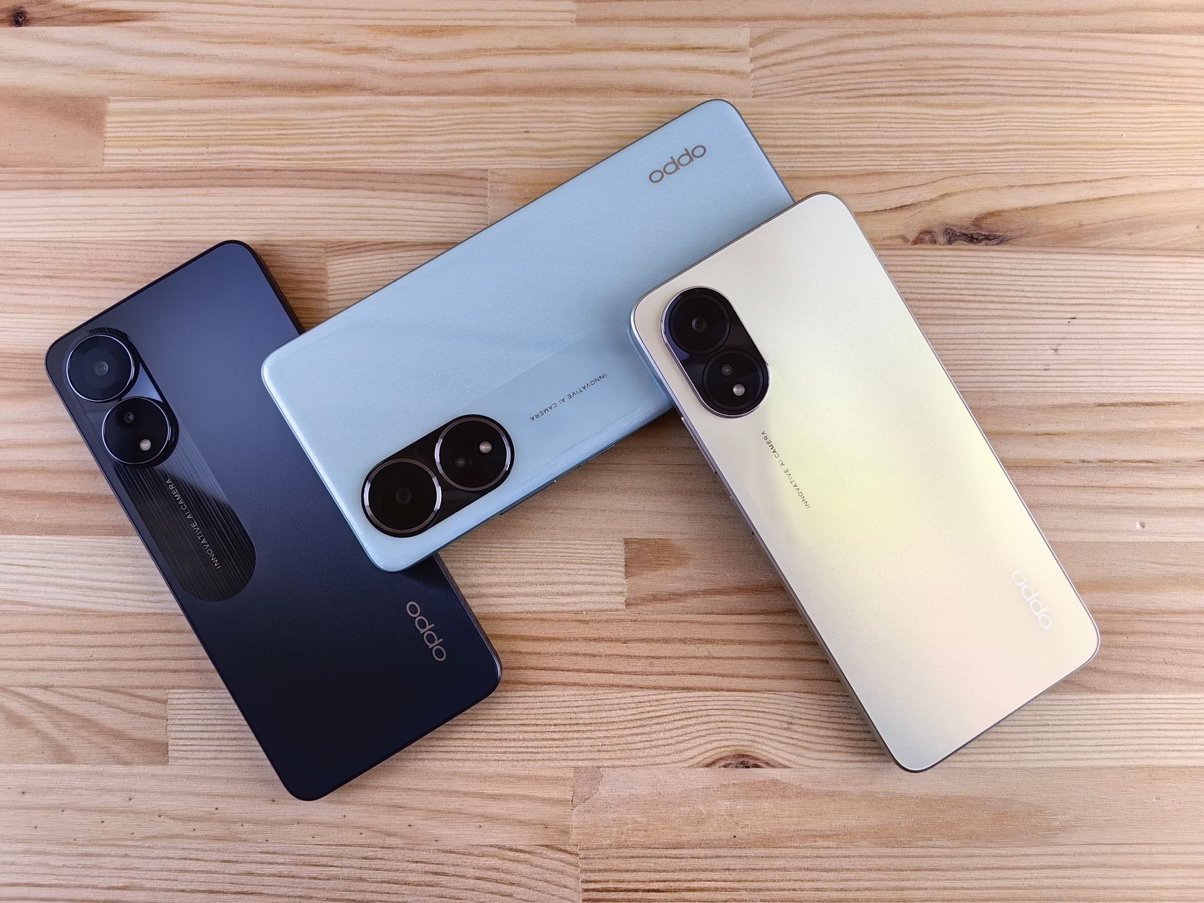 Minimalist flat lay of three smartphones on a wooden surface, showcasing sleek design and camera features.
