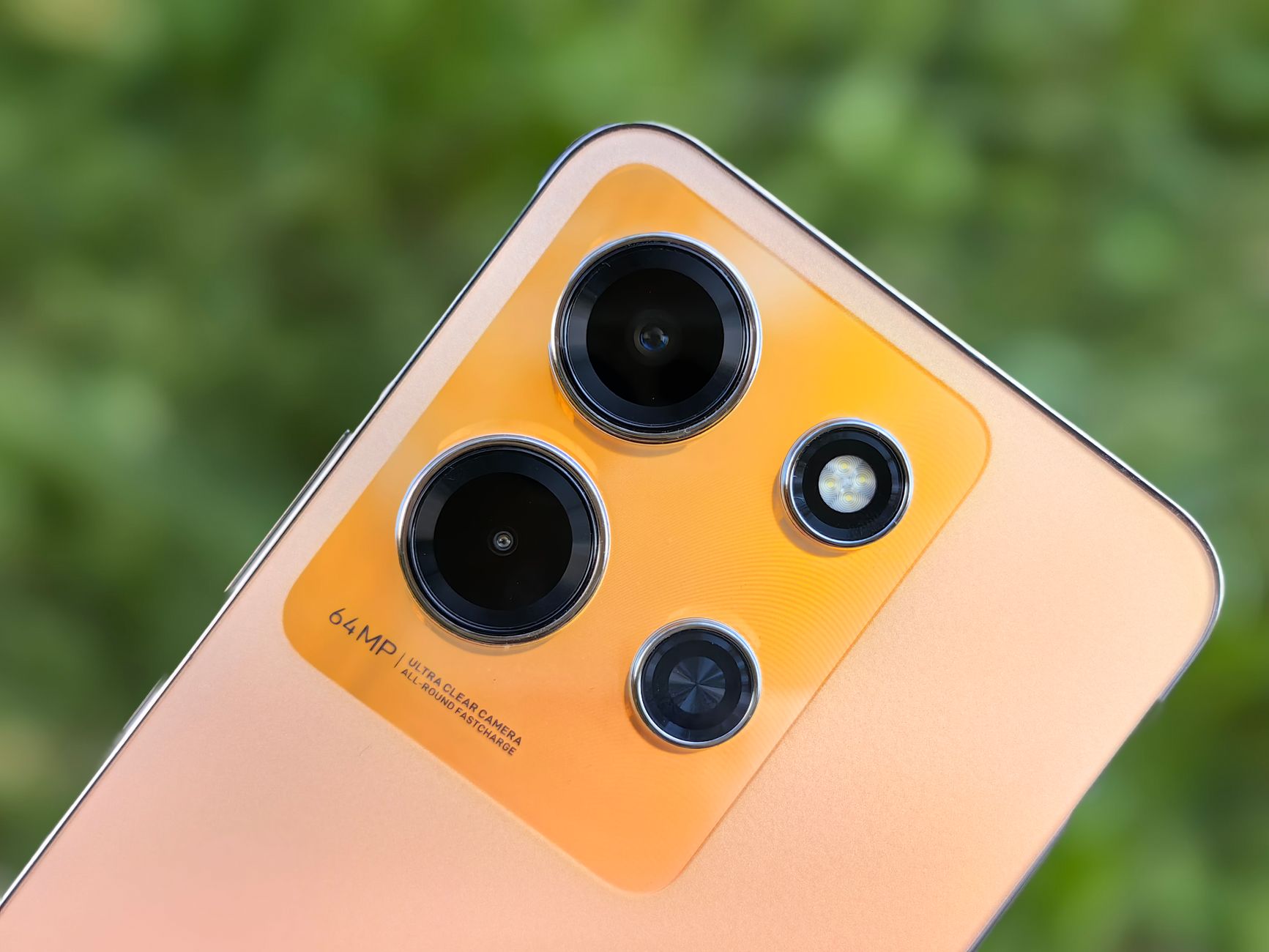Detailed close-up of a modern smartphone camera lens array against a blurred green background.