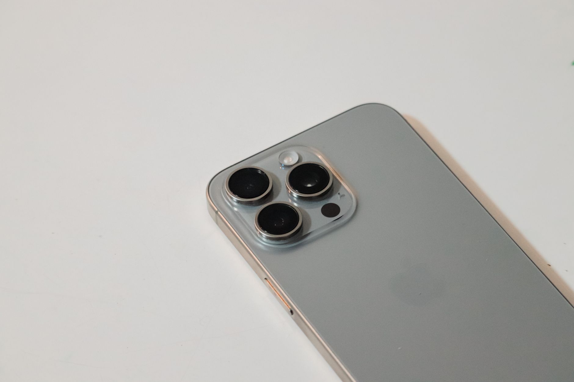 Detailed close-up of a sleek silver smartphone with triple camera lenses, on white background.