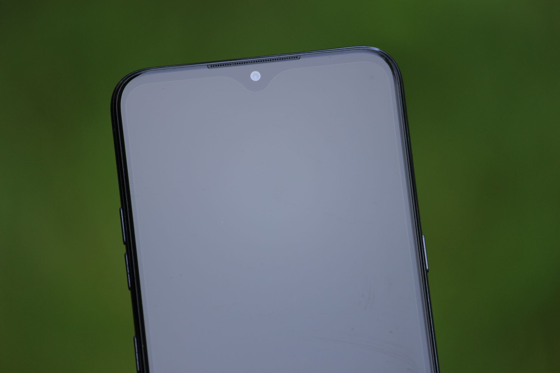Close-up shot of a new smartphone with a blank reflective screen outdoors.