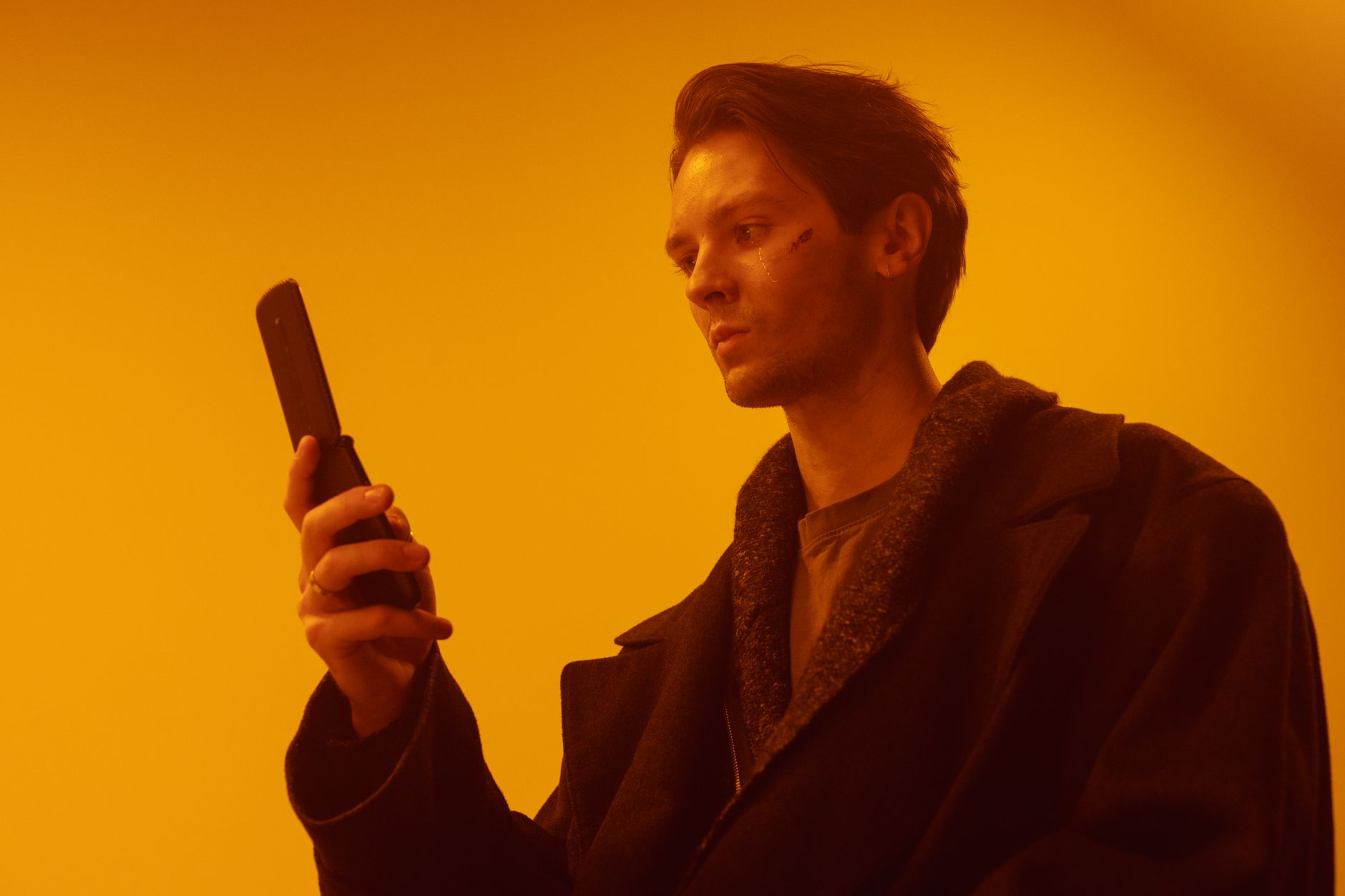 Dramatic studio portrait of a man using a vintage flip phone.